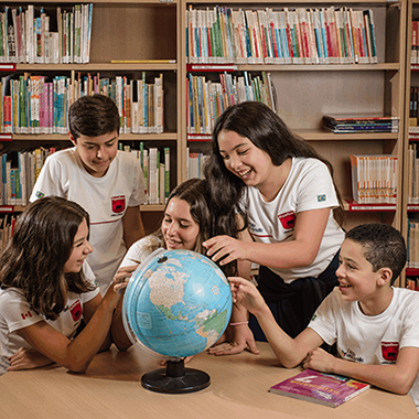 Estudantes do ensino fundamental da Maple Bear aprendem nomes de lugares em ingles, no globo terrestre.